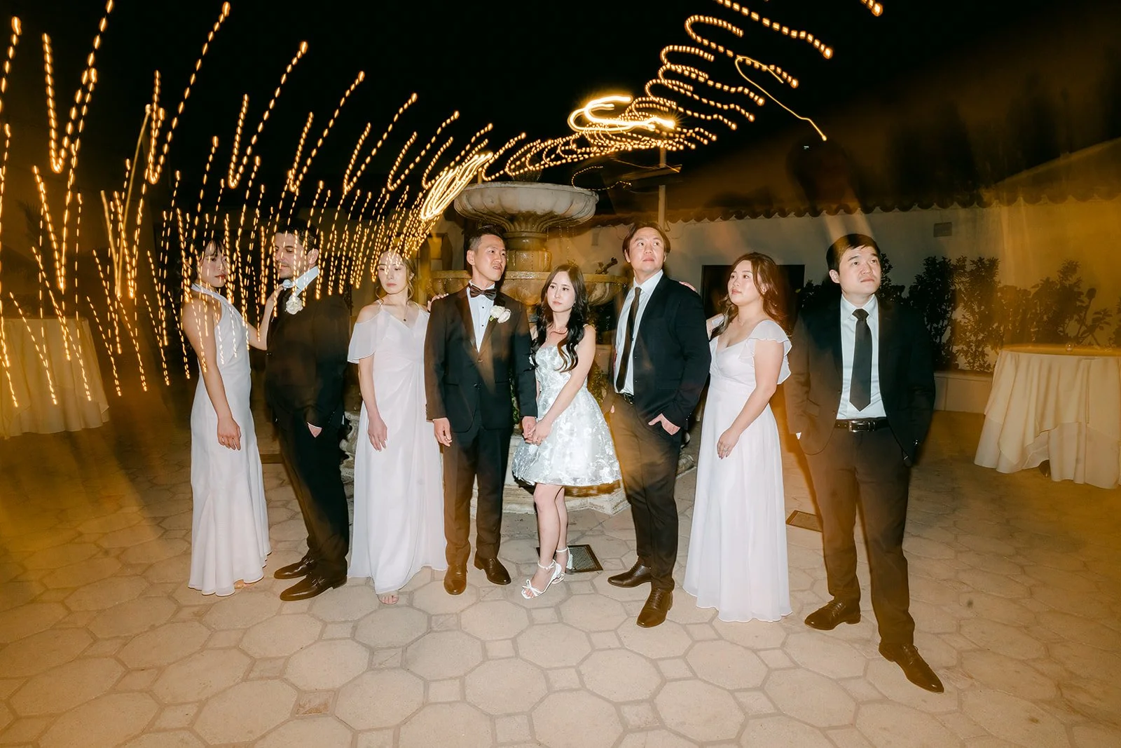 Wedding party under the courtyard string lights with light trails
