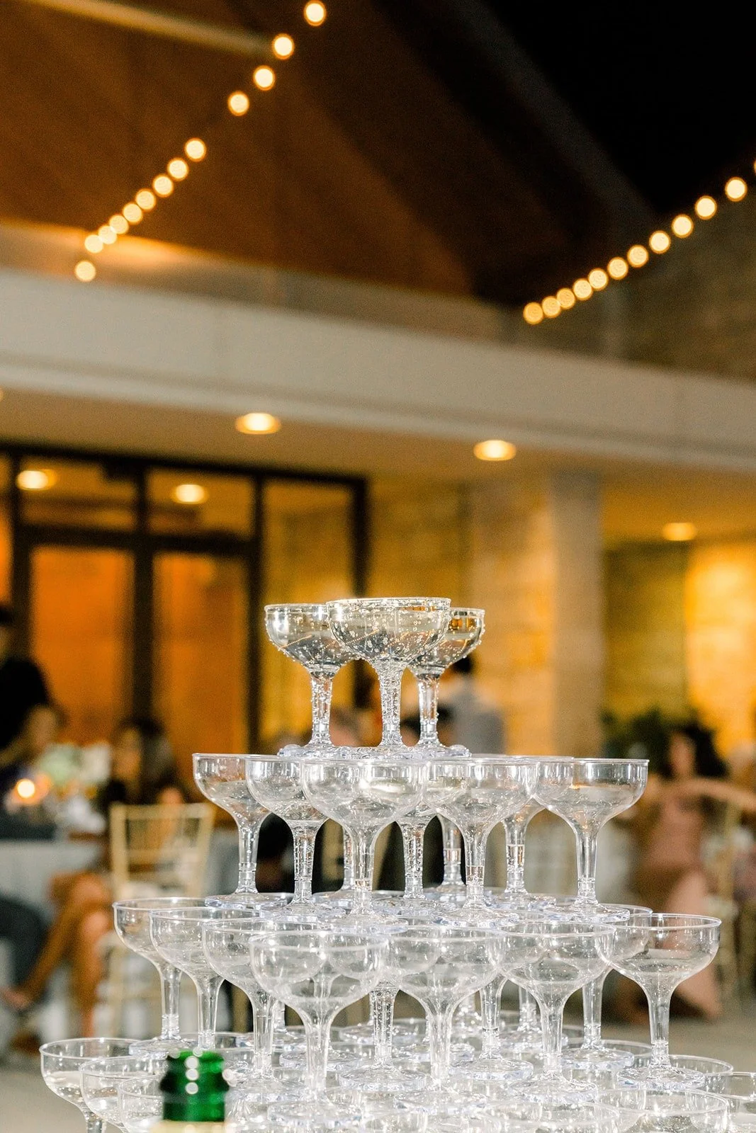 The champagne tower glowing under string lights at dusk, photographed by One and Only Production