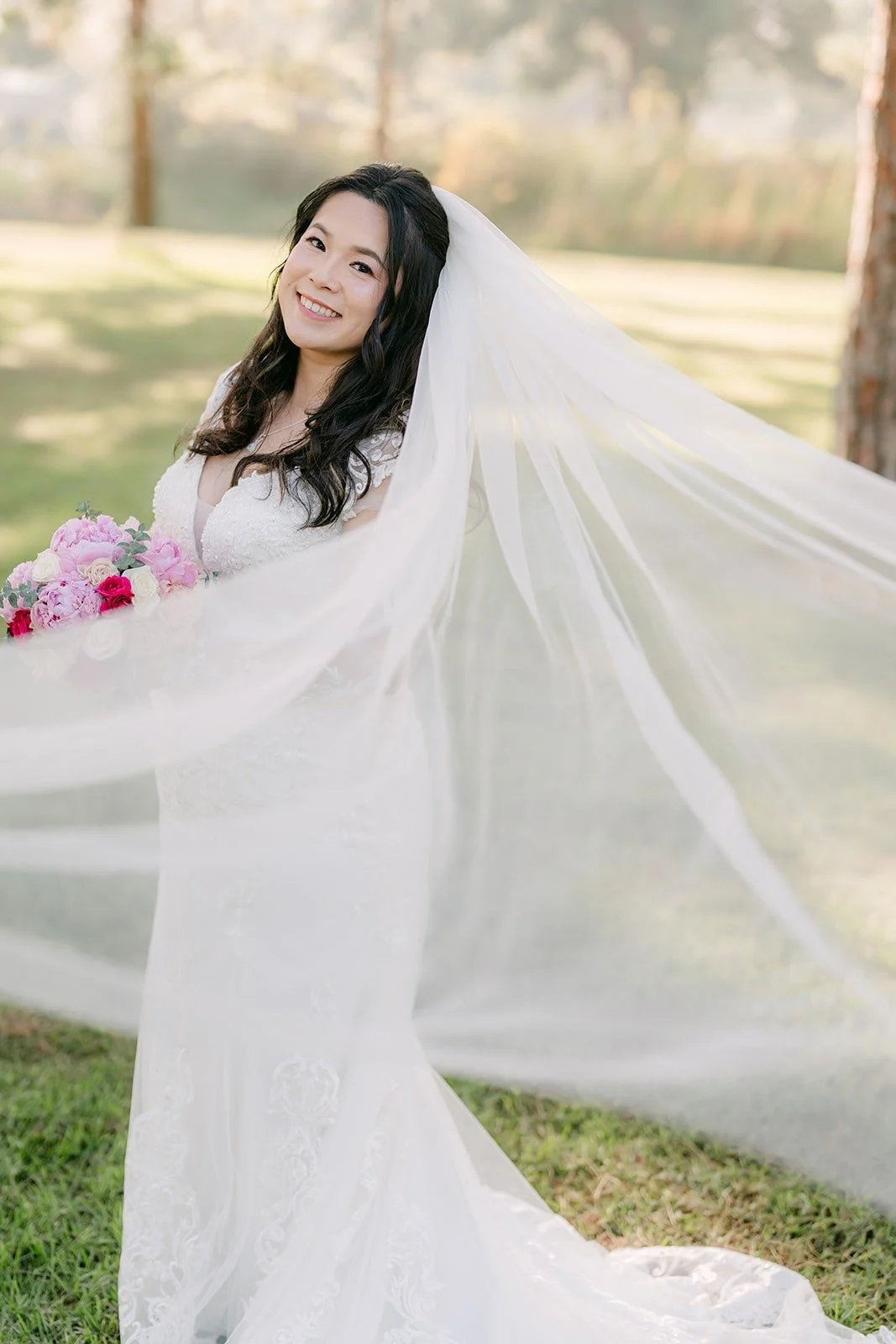 Amy's long veil catching the breeze under the trees
