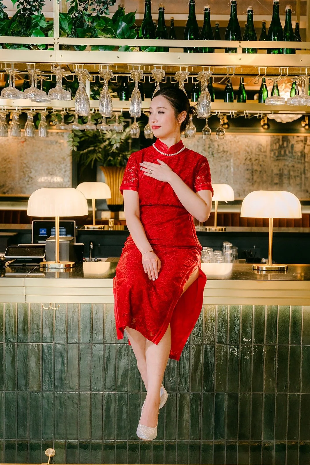 Elisa sits on the bar in her red qipao