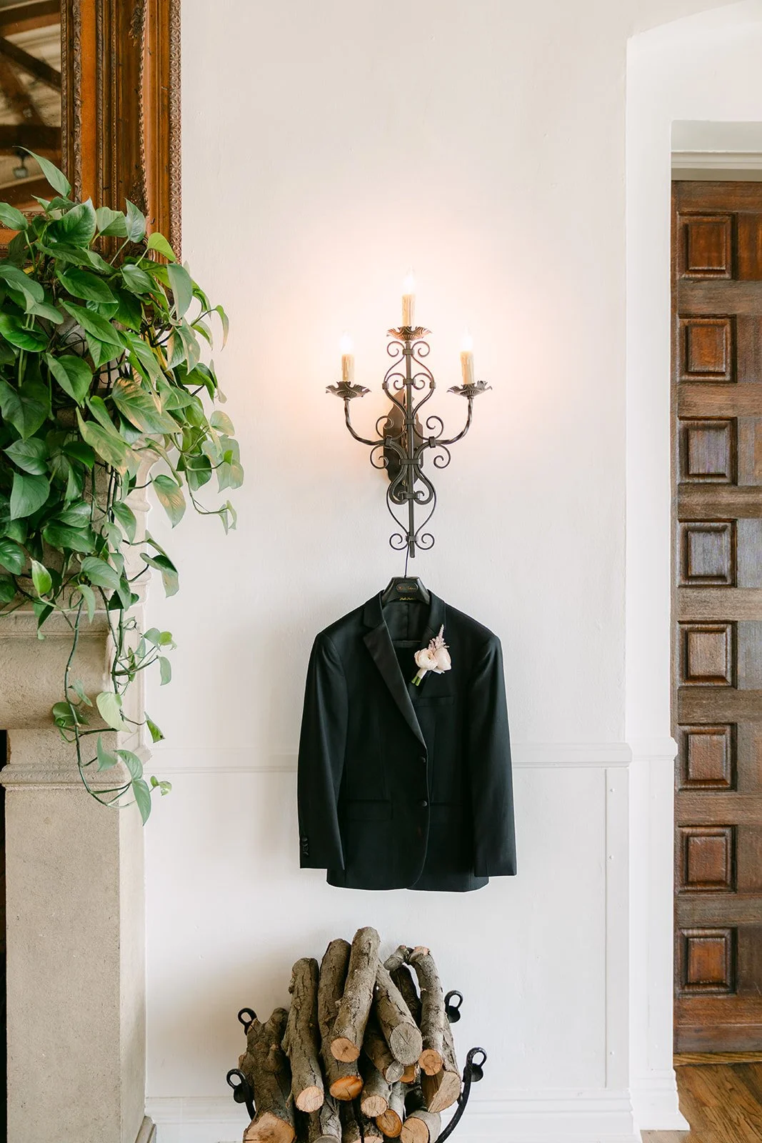 Groom's black tuxedo hanging below a wall sconce