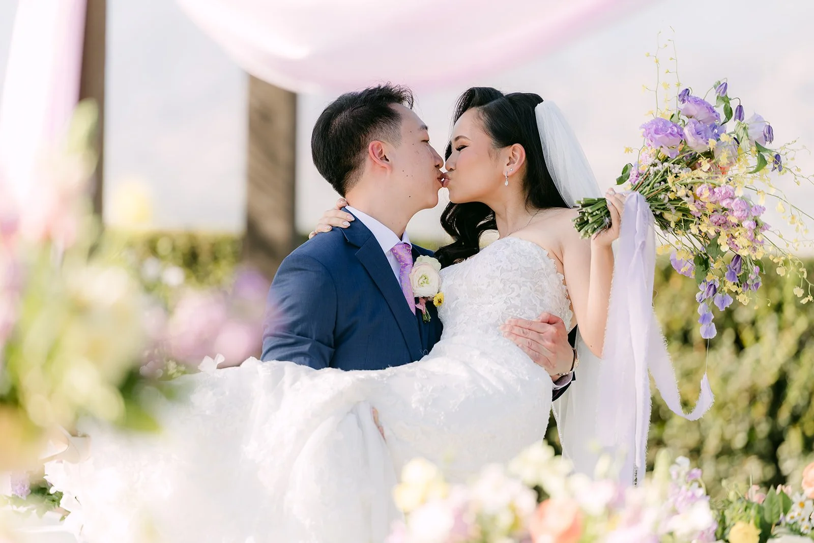 Elijah lifting Vannie for a kiss under the lilac draping.