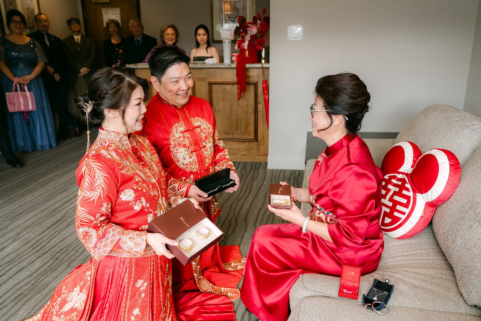 Sochi and Jay offer tea to a family member seated on the sofa
