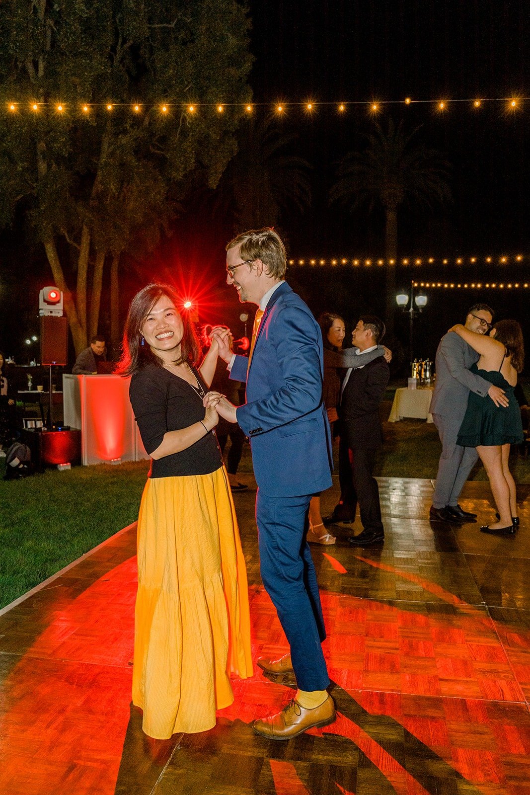 Alex dancing with a guest under the string lights
