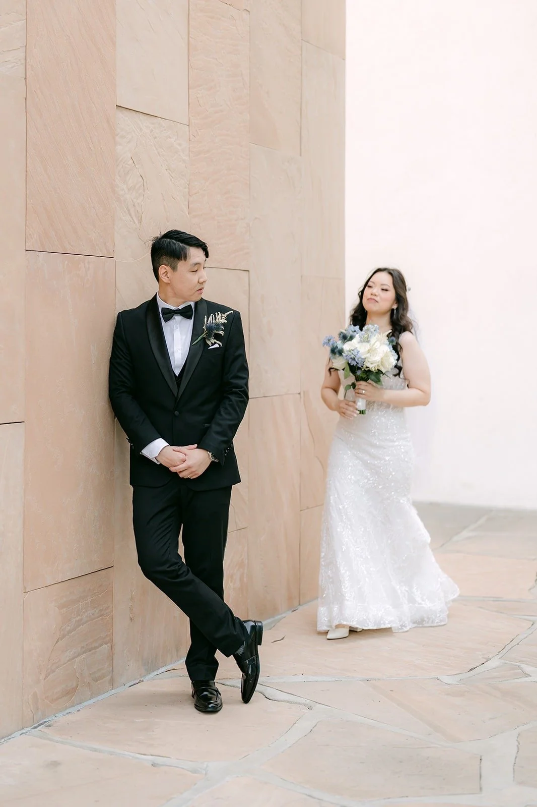 James leaning on the wall while Emily smiles back at him