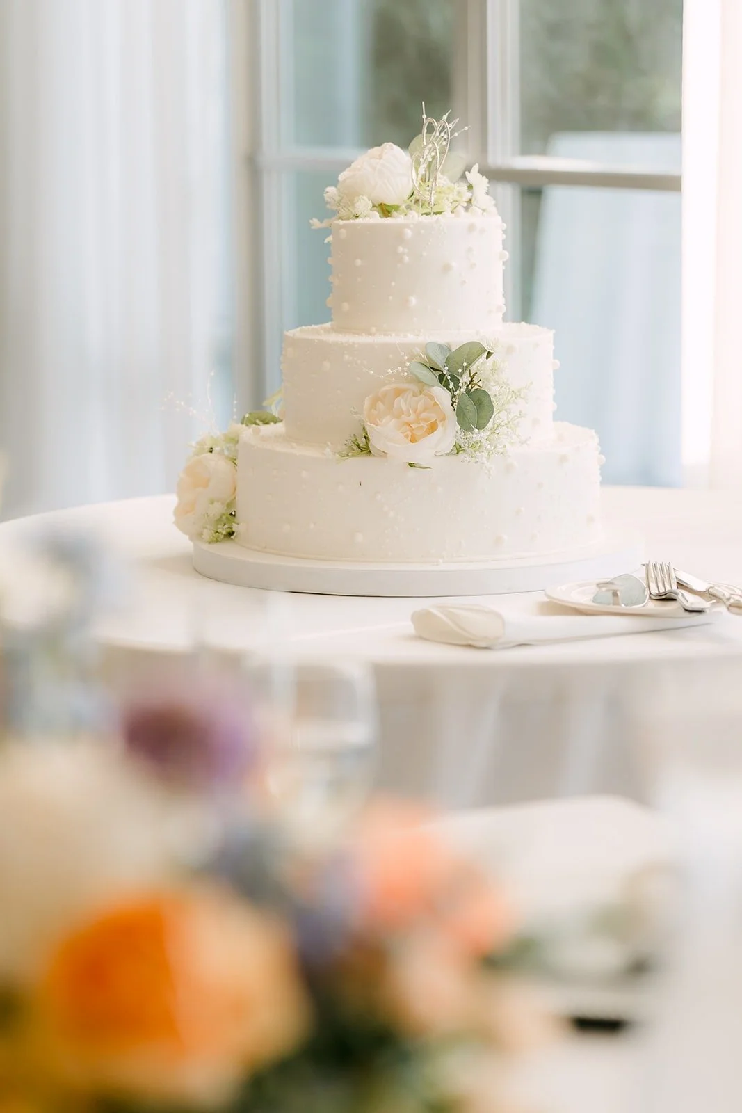 The white tiered wedding cake topped with flowers