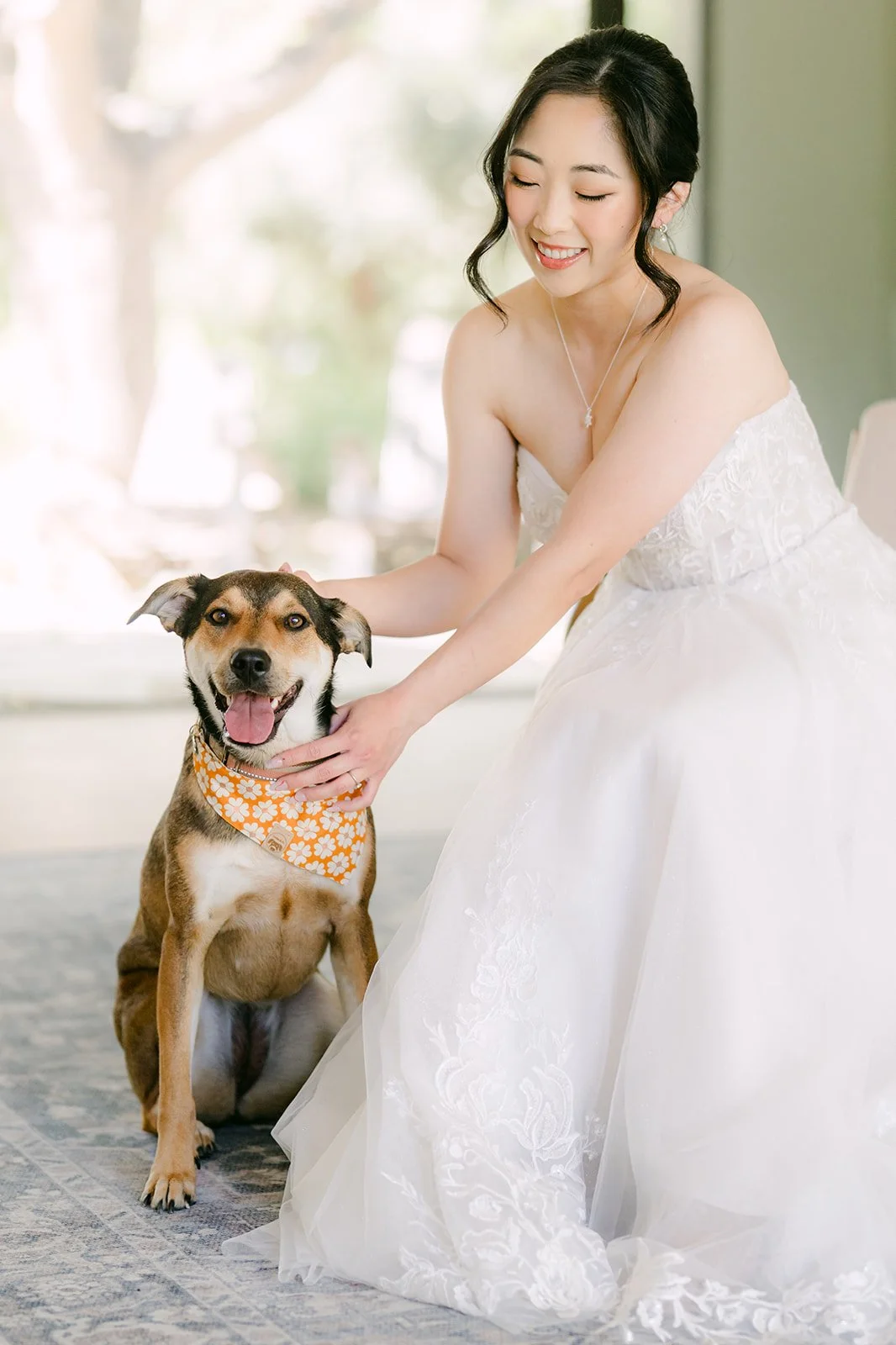 Bride smiling with Bagel the dog in her bridal suite