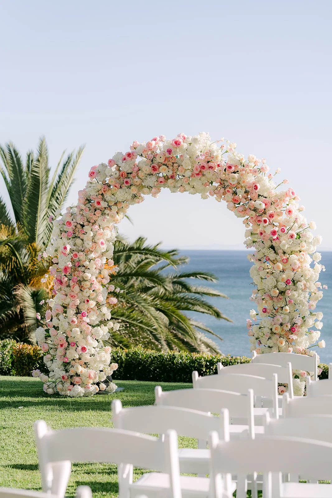 Blush and ivory rose arch overlooking the Pacific Ocean