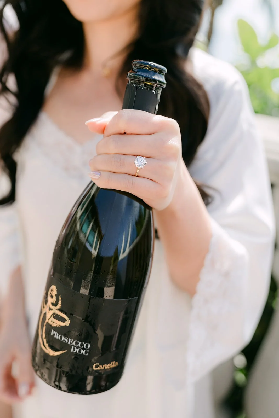 Bride holding a champagne bottle with her engagement ring in view