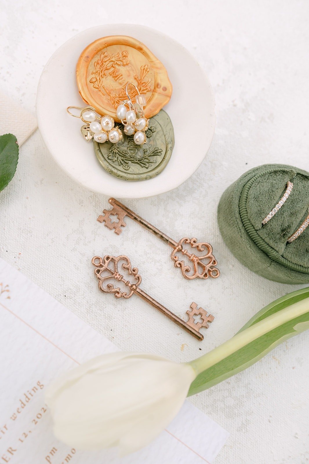 Antique keys, a green ring box and wax seals styled on a white table