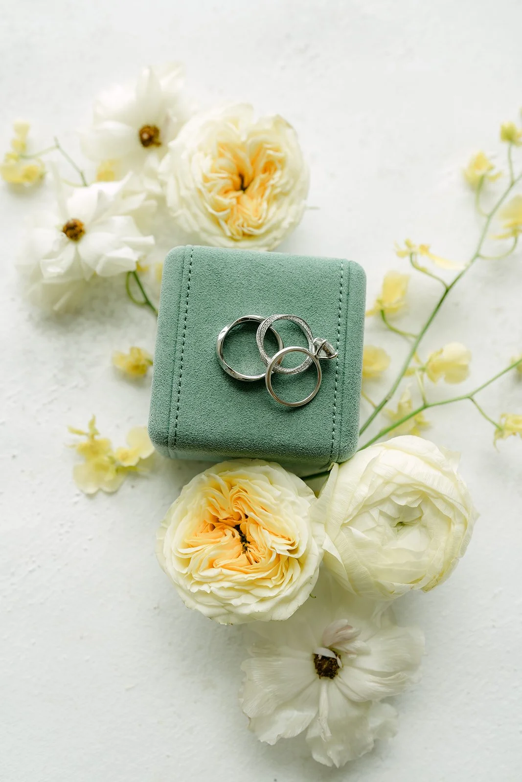 Green velvet ring box with the wedding rings and yellow garden roses.