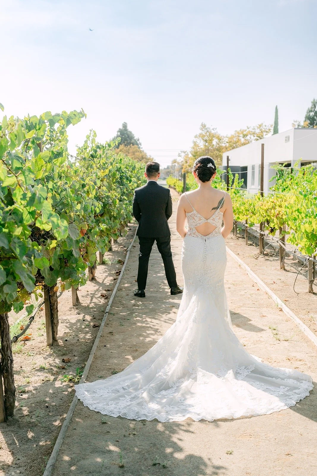 Xuemin walking up behind Alex in the vineyard for their first look