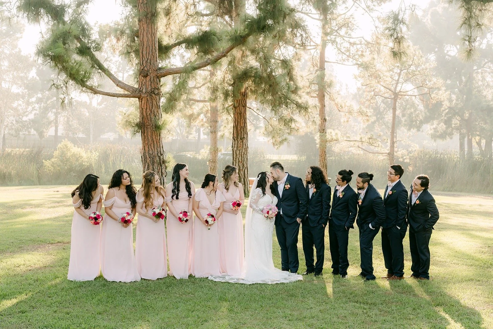 Wedding party with arms raised under the pines