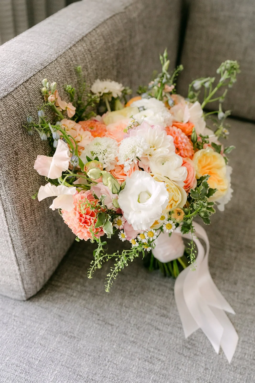 Amanda's spring bouquet of peach, white and pink blooms resting on a chair.
