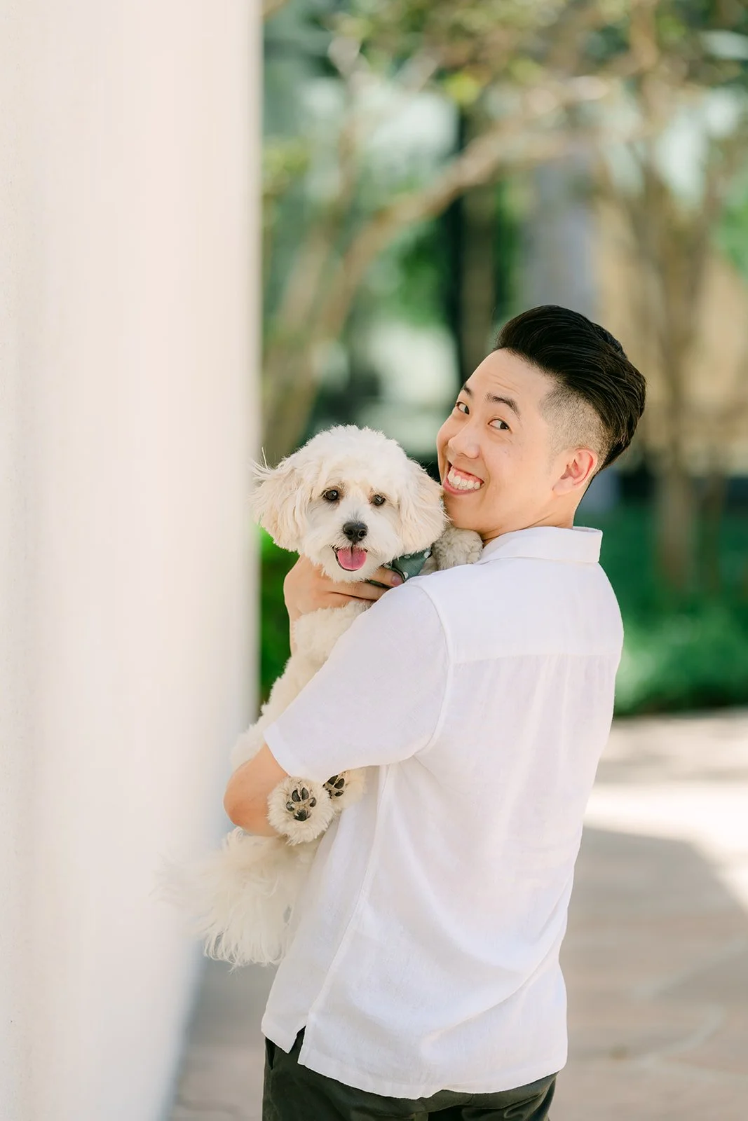 Alan smiles while holding Tofu against the white wall.