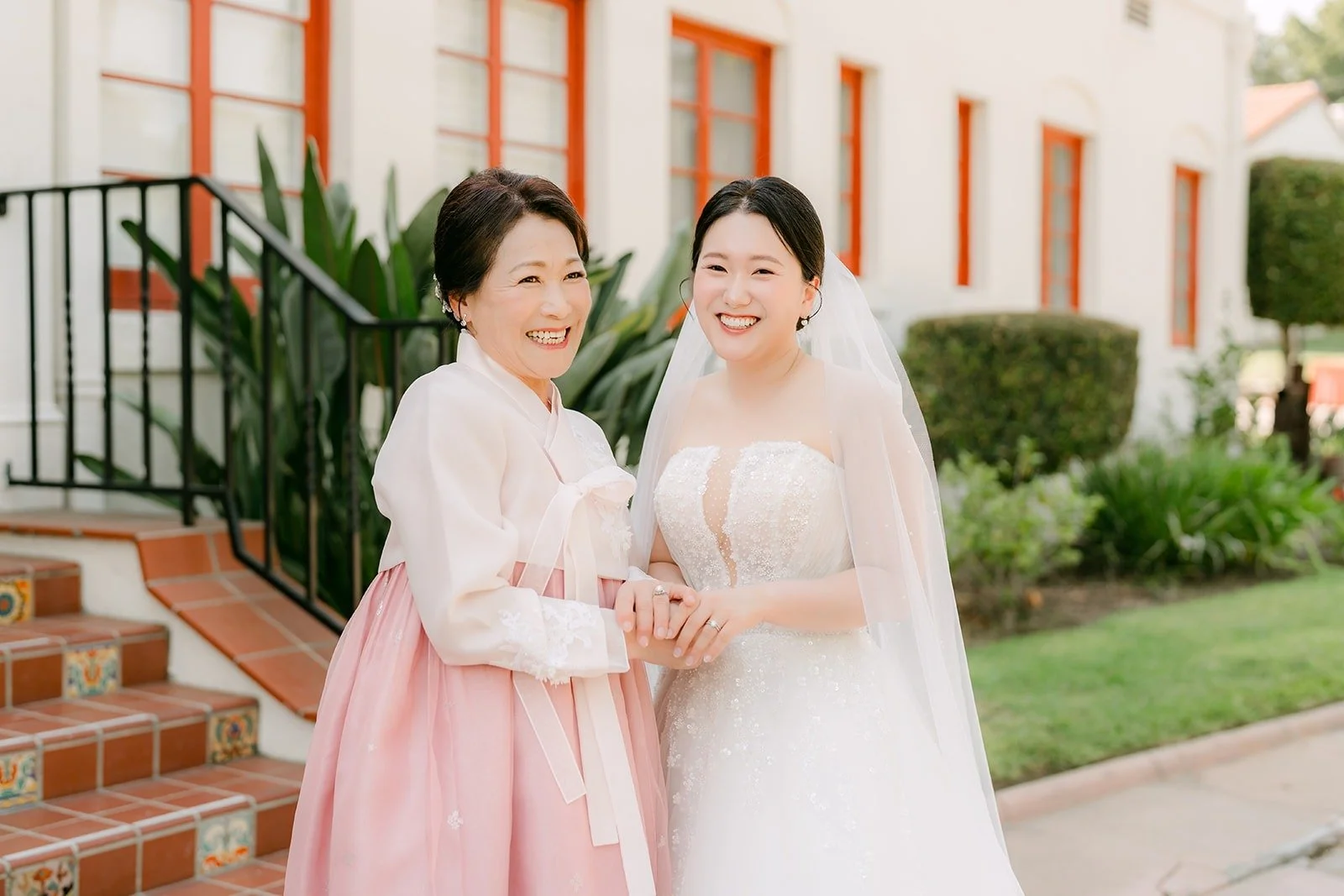 Amy with her mom in a pink hanbok outside the mansion