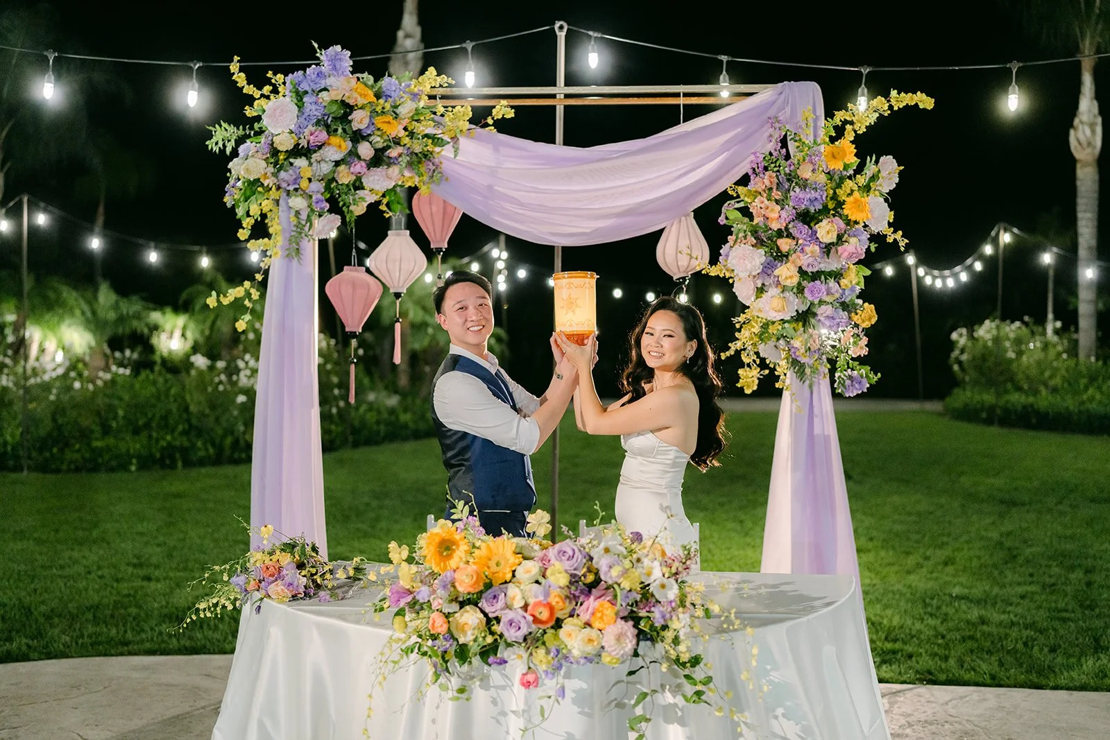 The sweetheart table at night under string lights with the lantern glowing, photographed by One and Only Production.