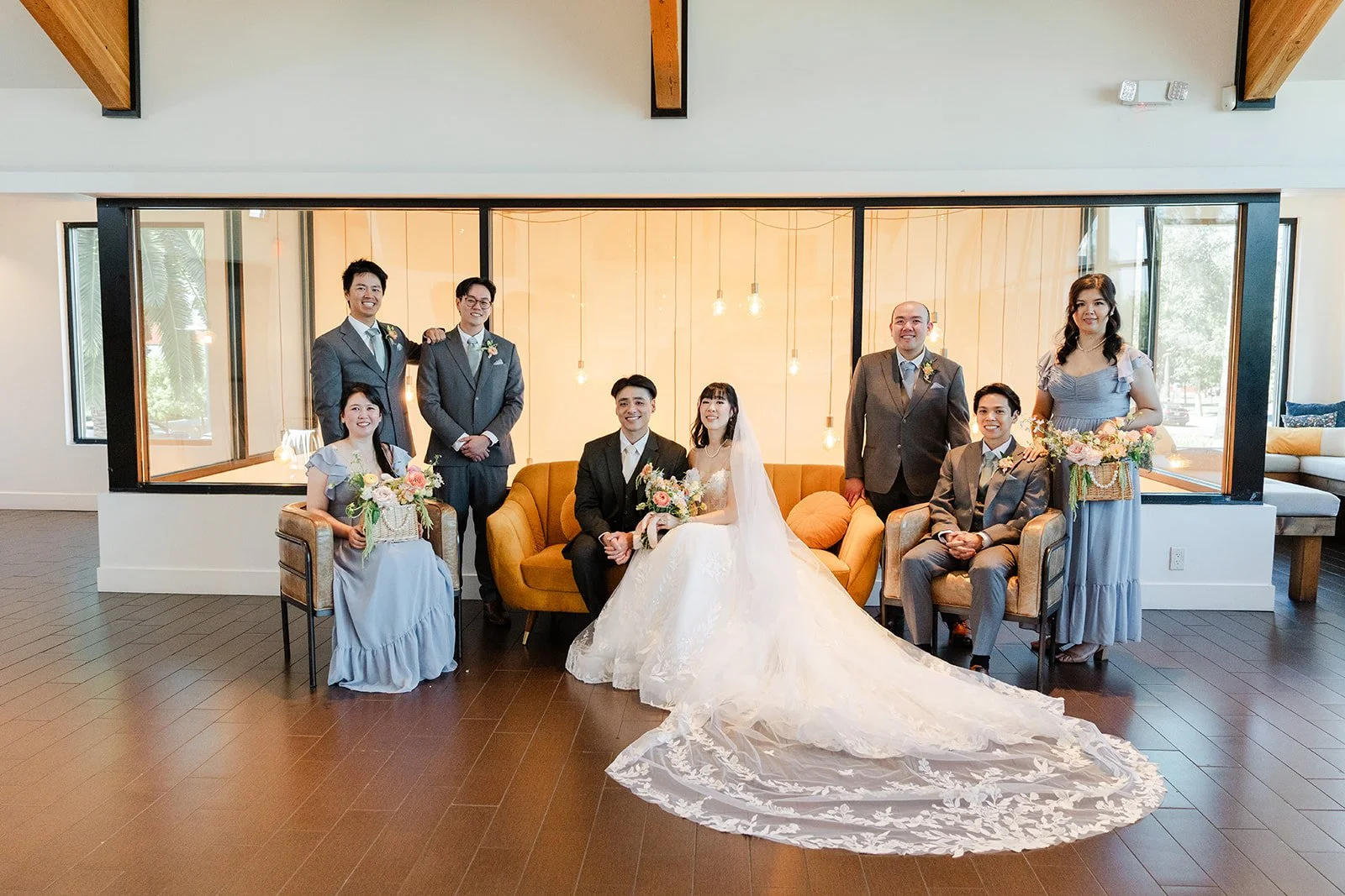 Full wedding party gathered around the mustard sofa at The Colony House