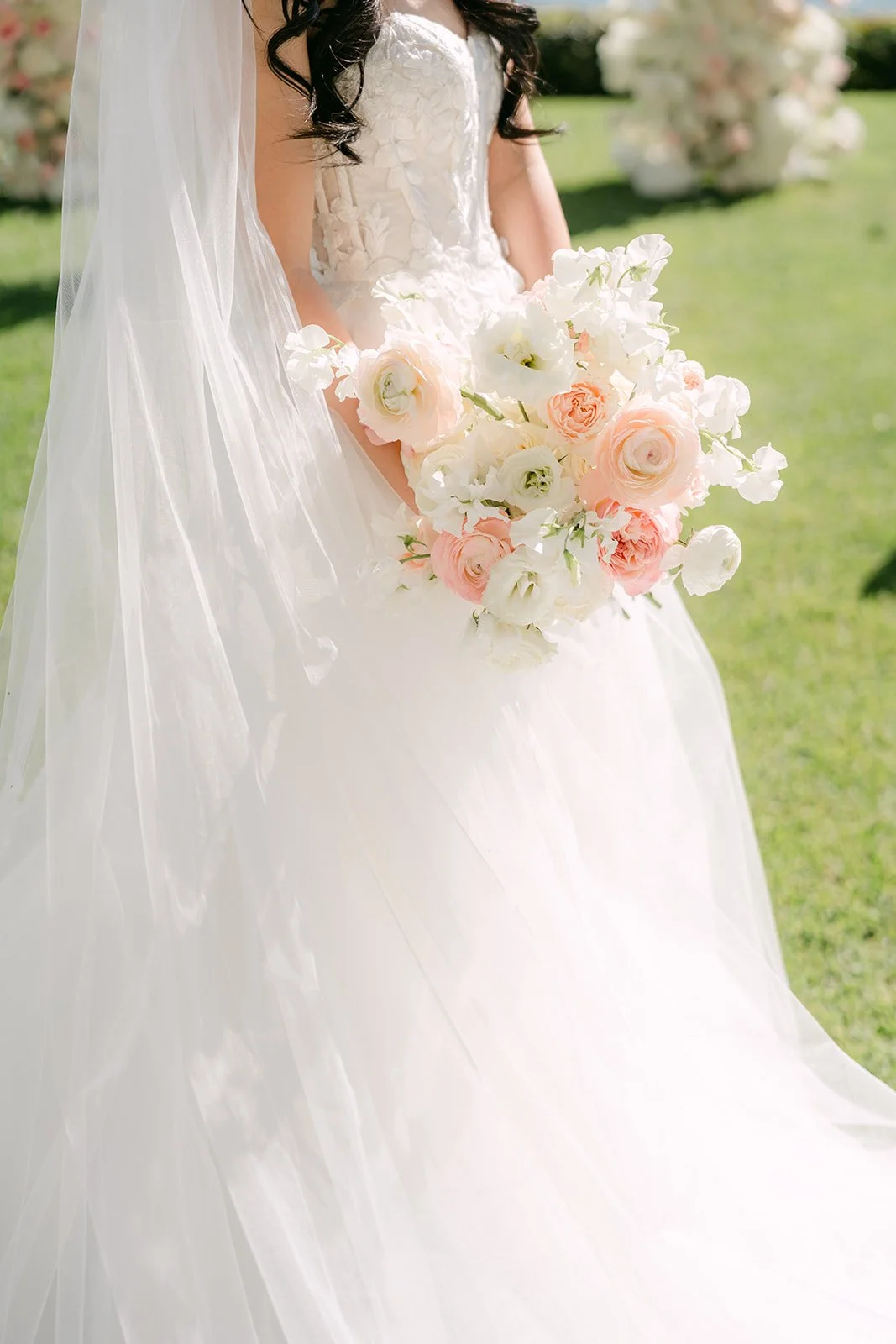 Bride holding her blush rose bouquet against her veil