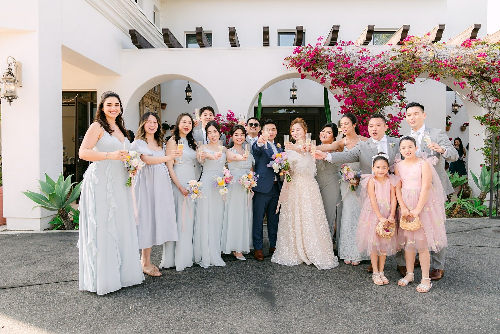 Joanna and Jerrick with their wedding party and flower girls under the bougainvillea