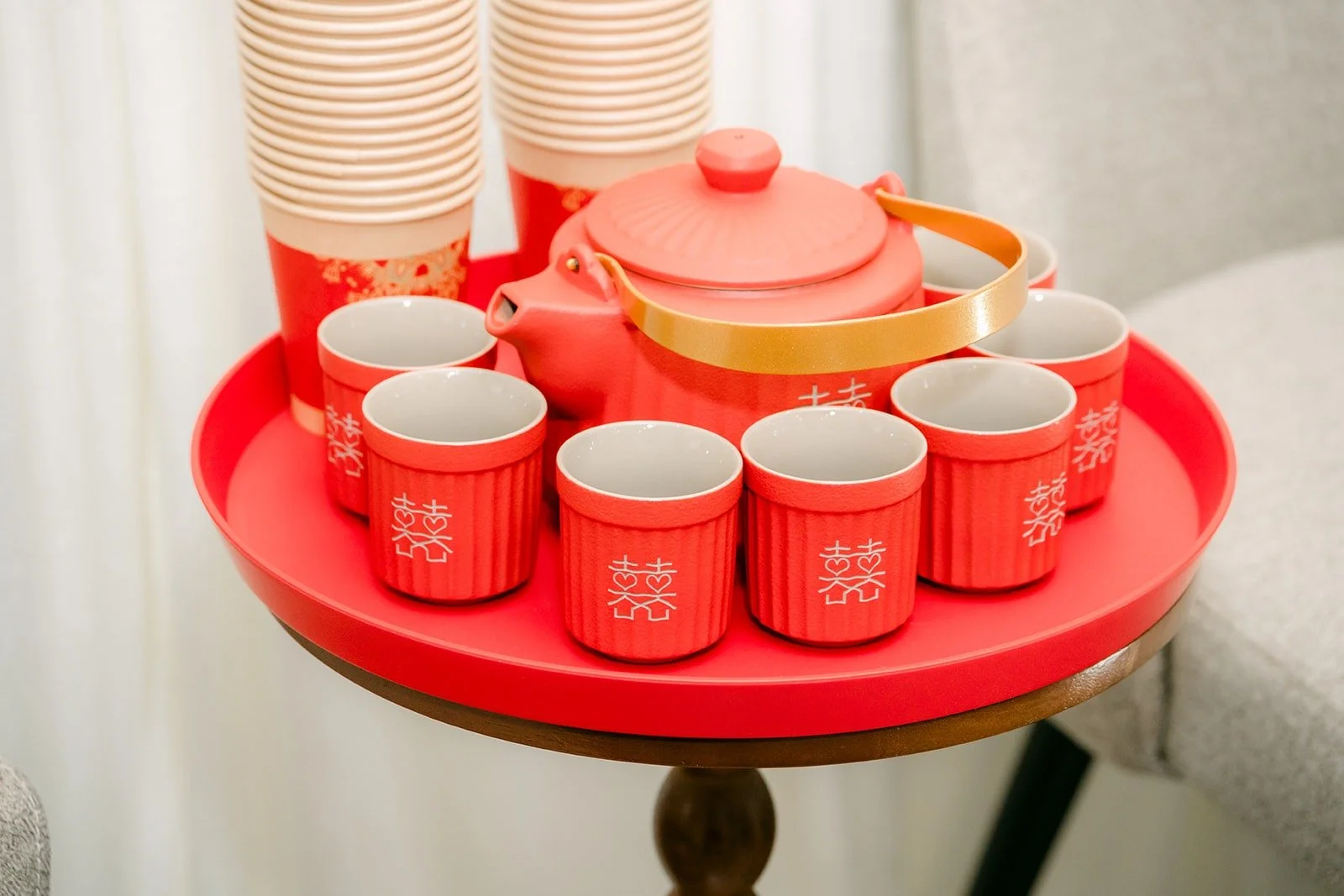 A red tea set with a teapot and cups on a round red tray