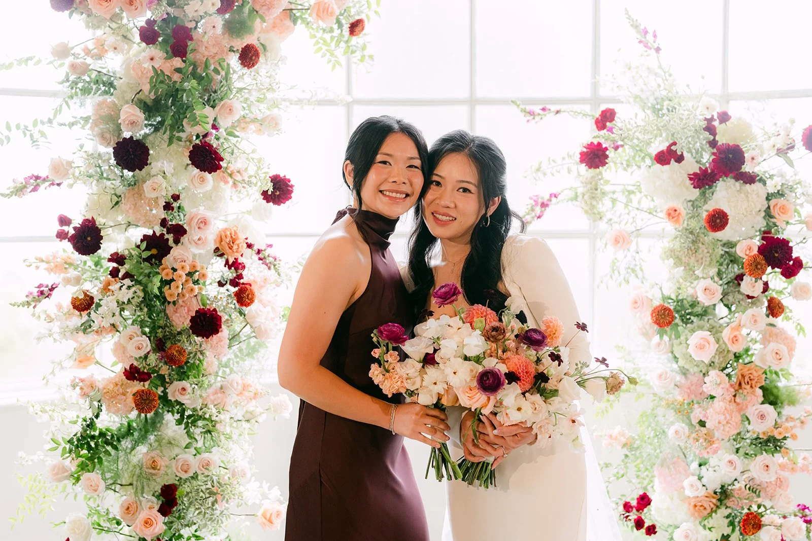 Denise and her sister smiling with matching bouquets.