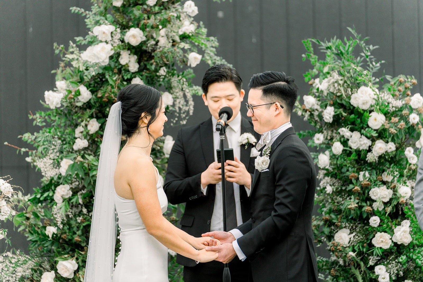 Cindy and Alex hold hands between the floral columns