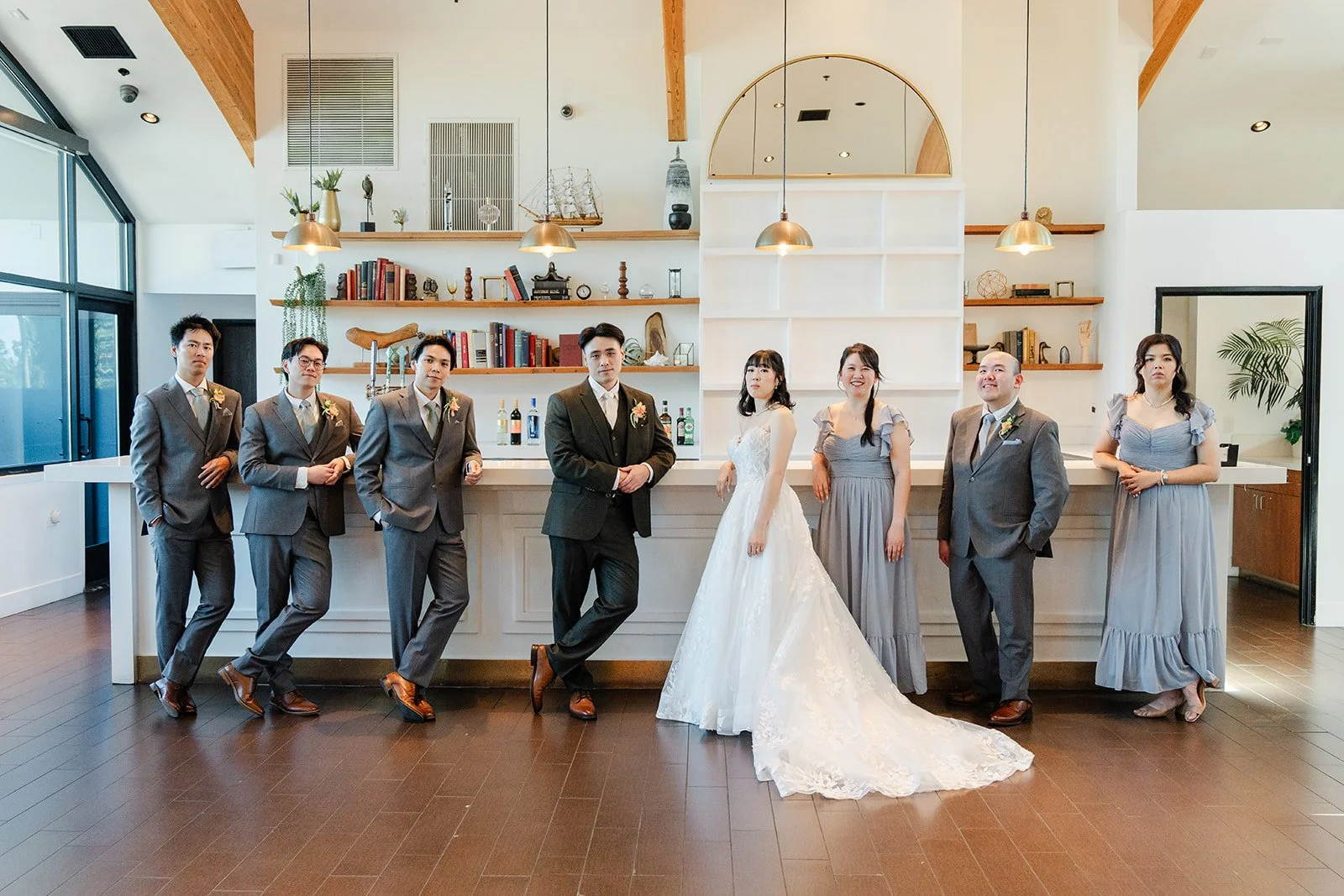 Wedding party lined up in front of the bar shelves at The Colony House