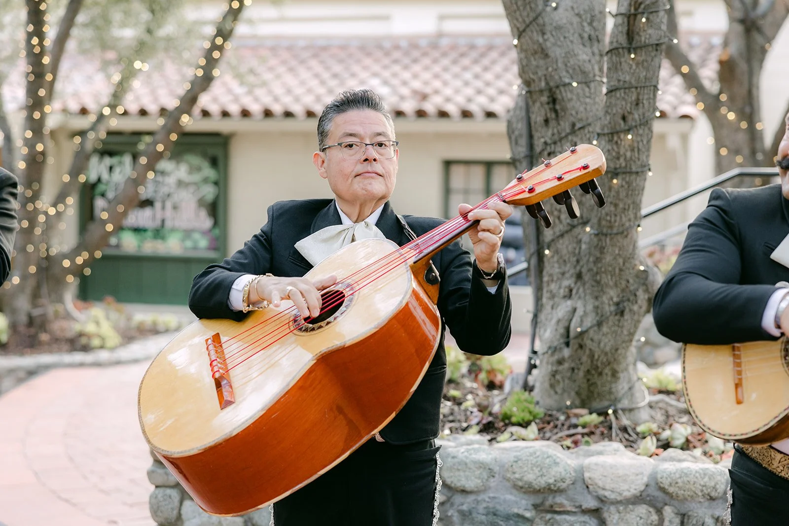 A mariachi guitarrón player performing as guests arrive