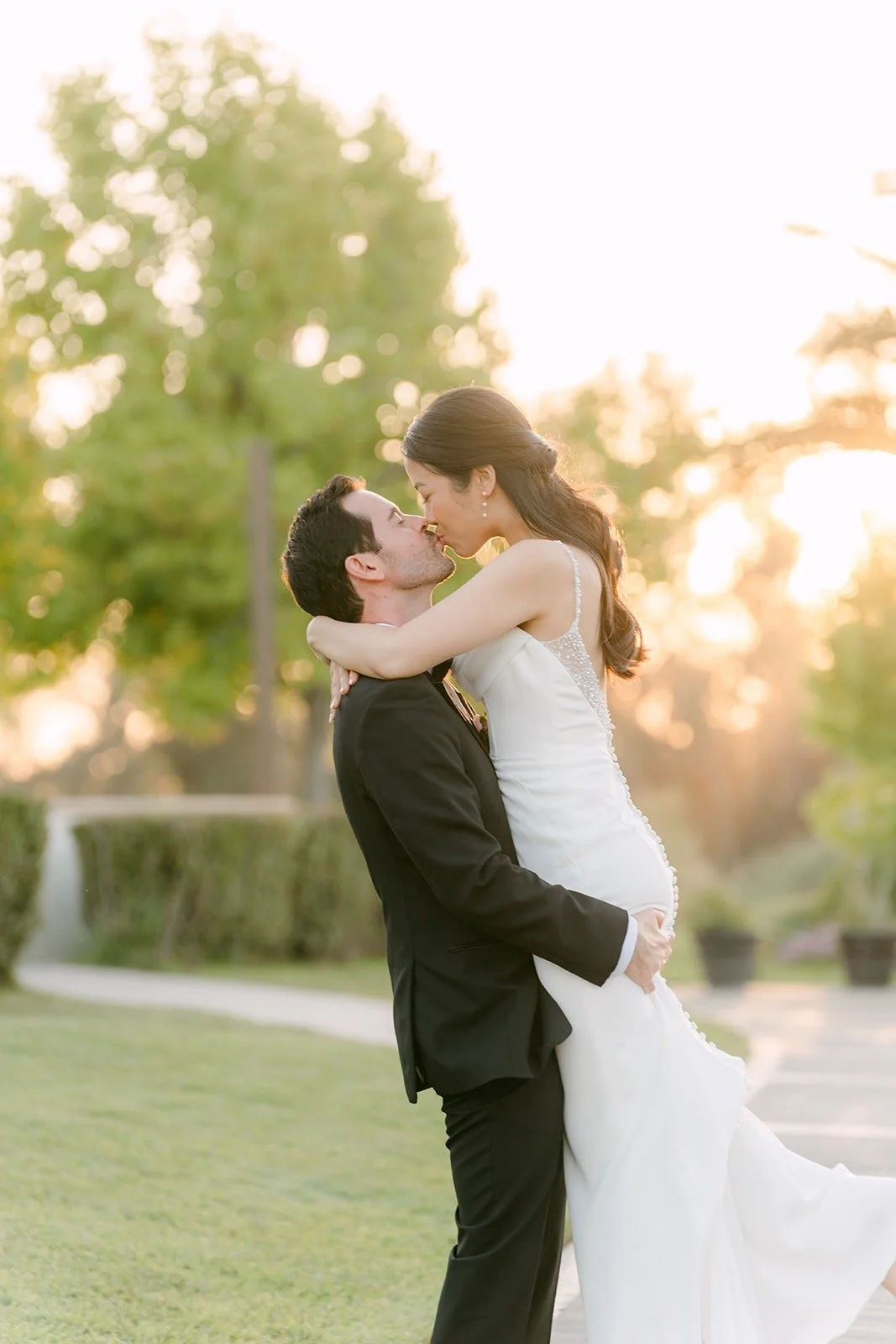 Kevin lifting Stephanie off the ground in front of the trees