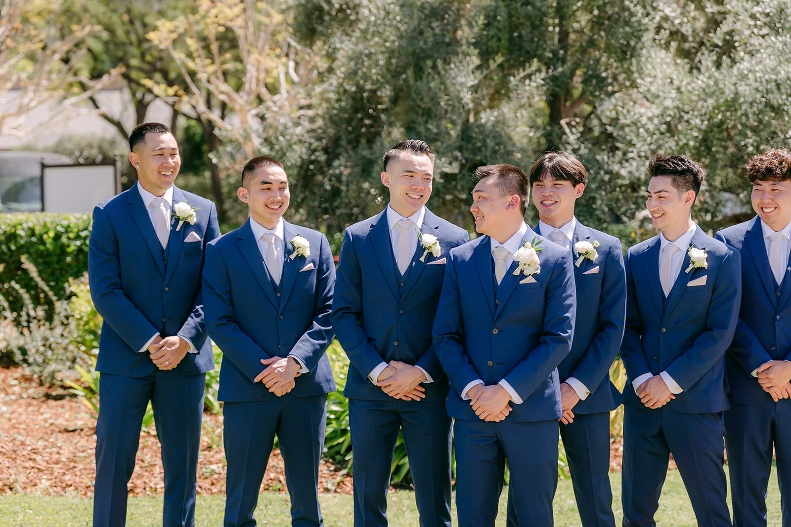 Alex and his groomsmen in navy suits lined up on the lawn at Los Robles Greens