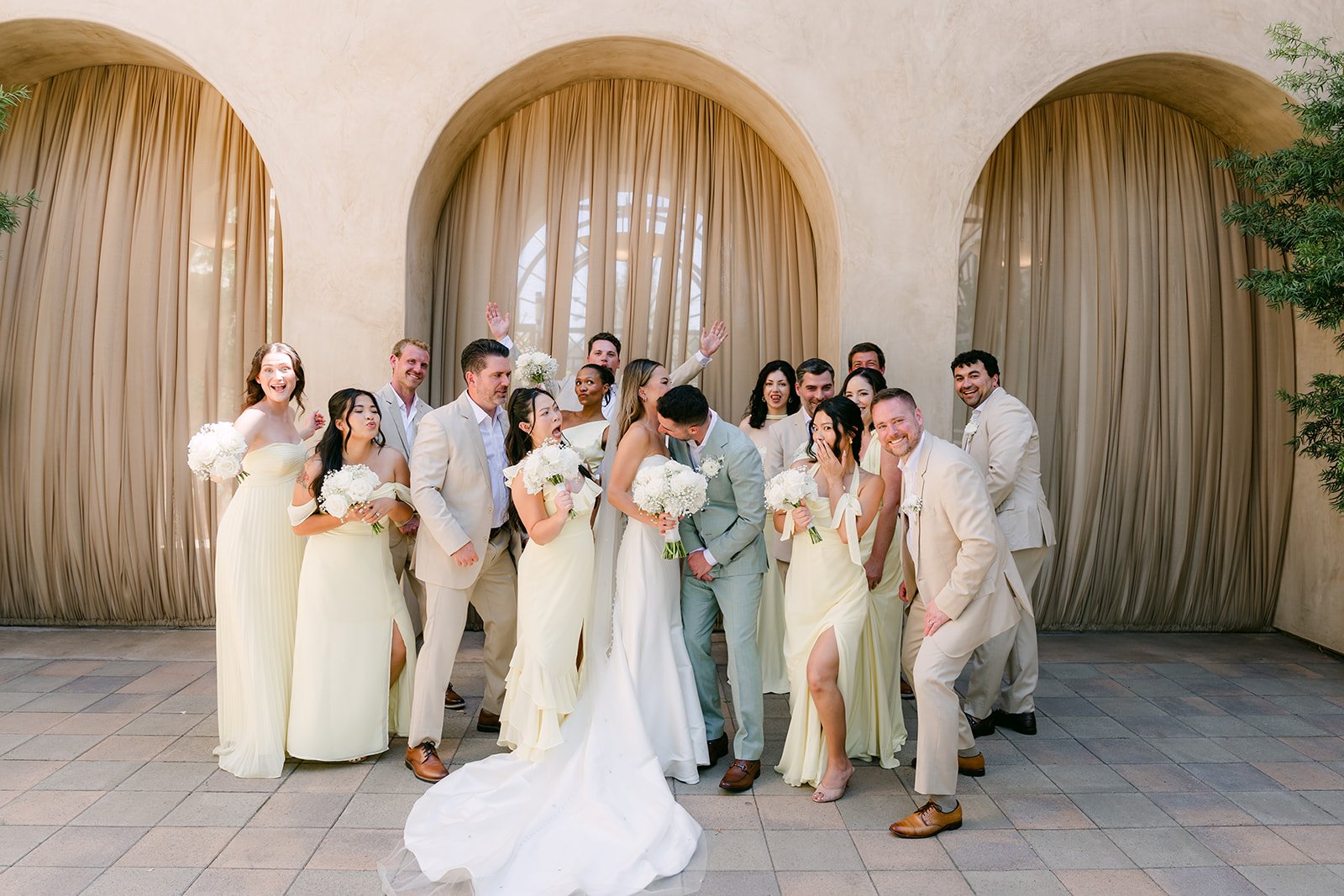 Wedding party celebrating with raised bouquets under the arches