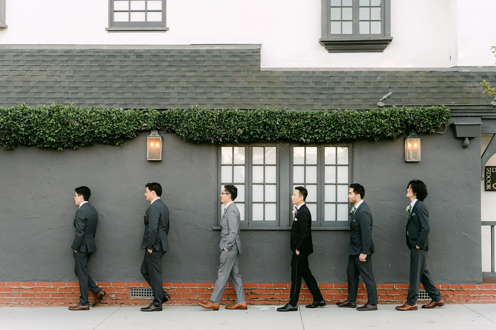 Jason and his groomsmen walking past the grey wall at Five Crowns