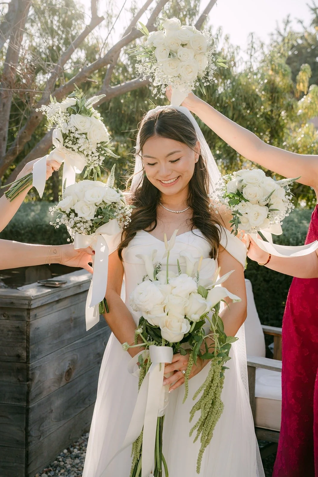 Bridesmaids raising their white bouquets around Jadee