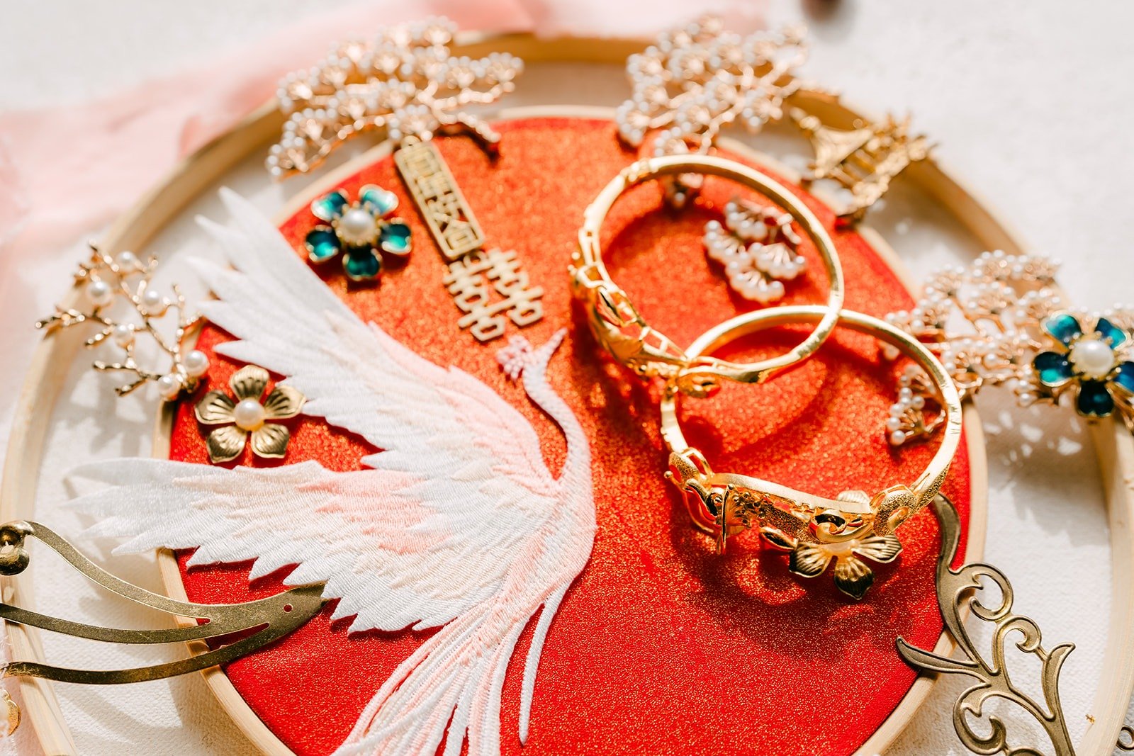 A white crane embroidered fan holding gold bangles and rings
