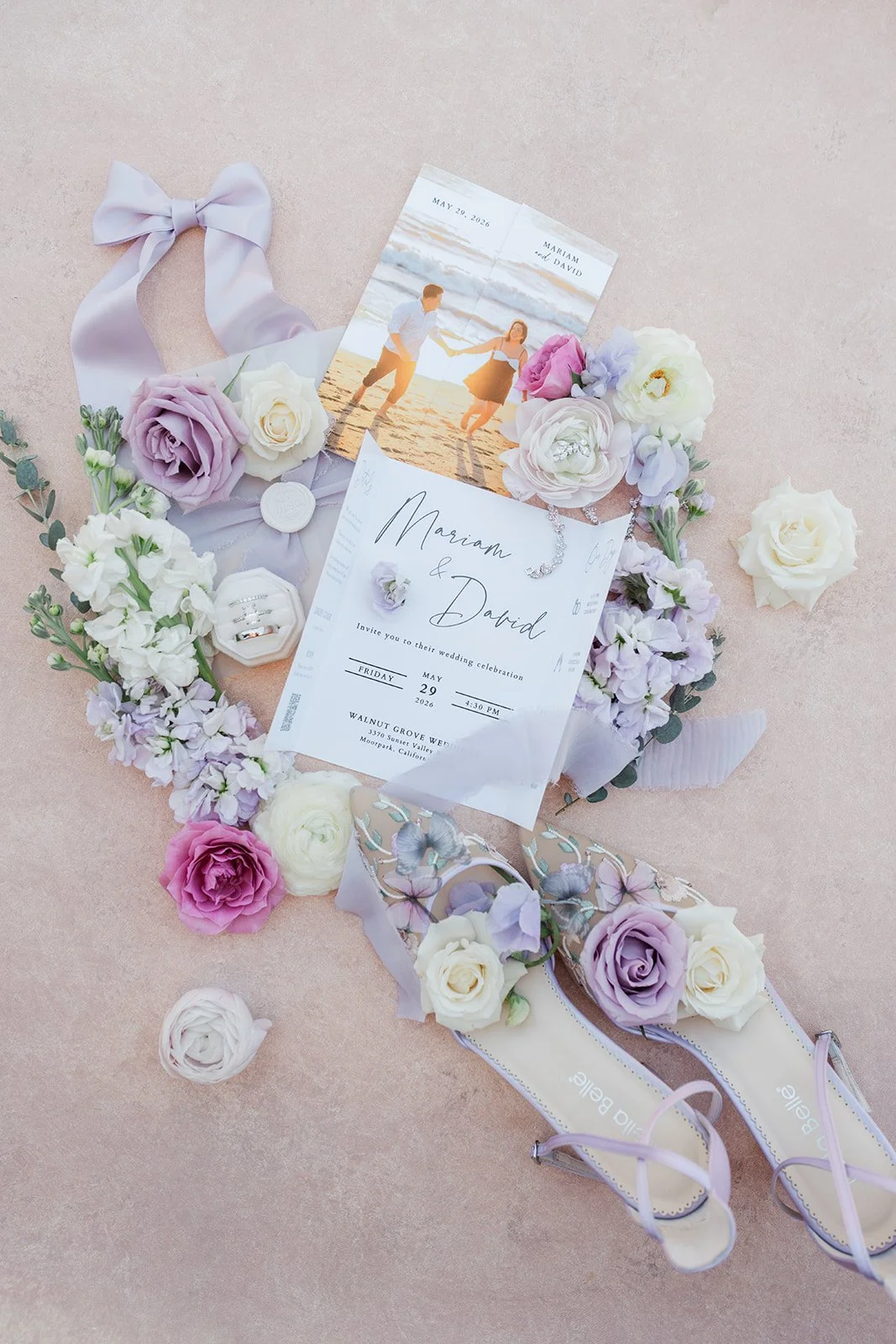 Lavender wedding invitation flat lay with ribbon and roses