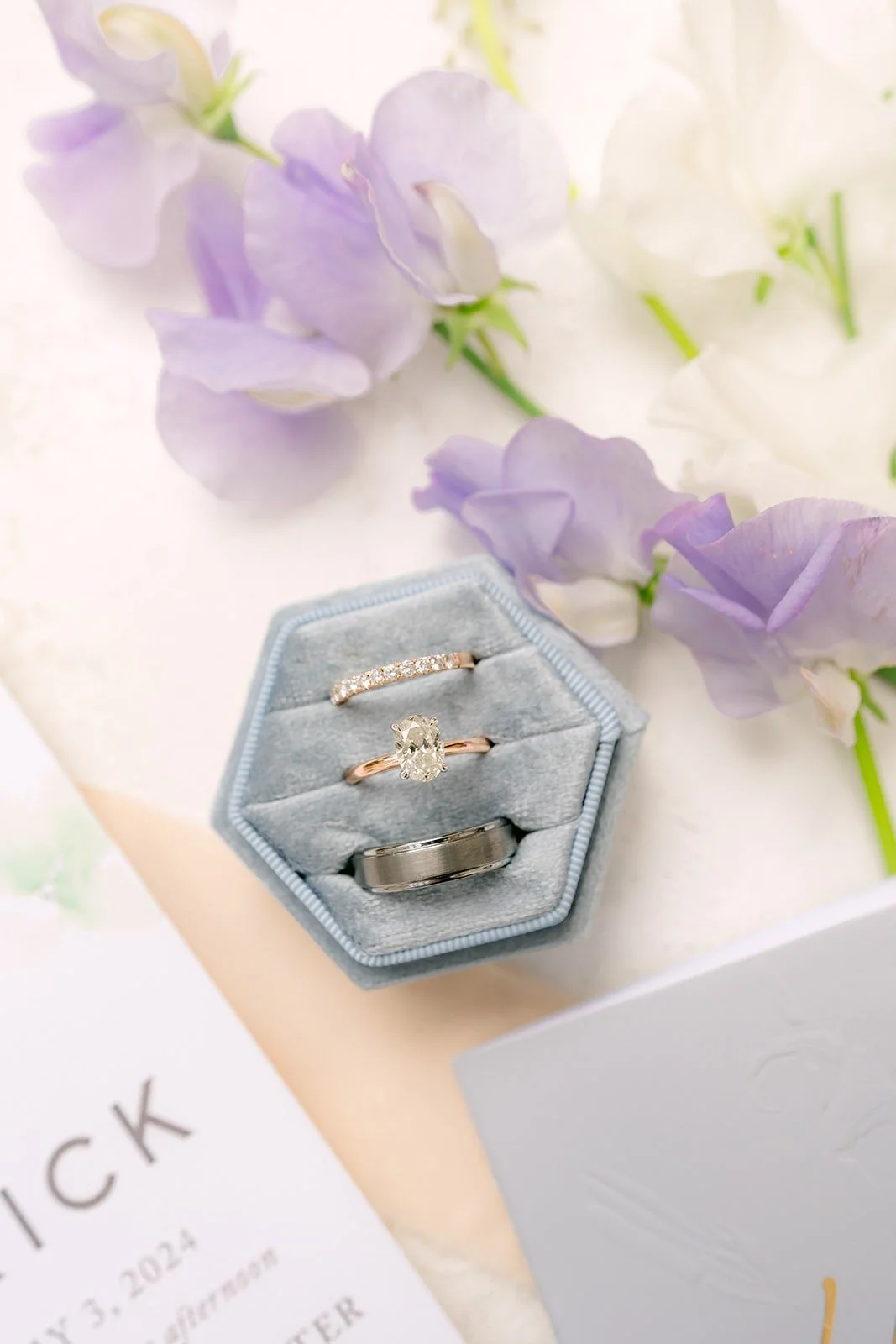 The rings in a dusty blue velvet hexagon box among lavender sweet peas