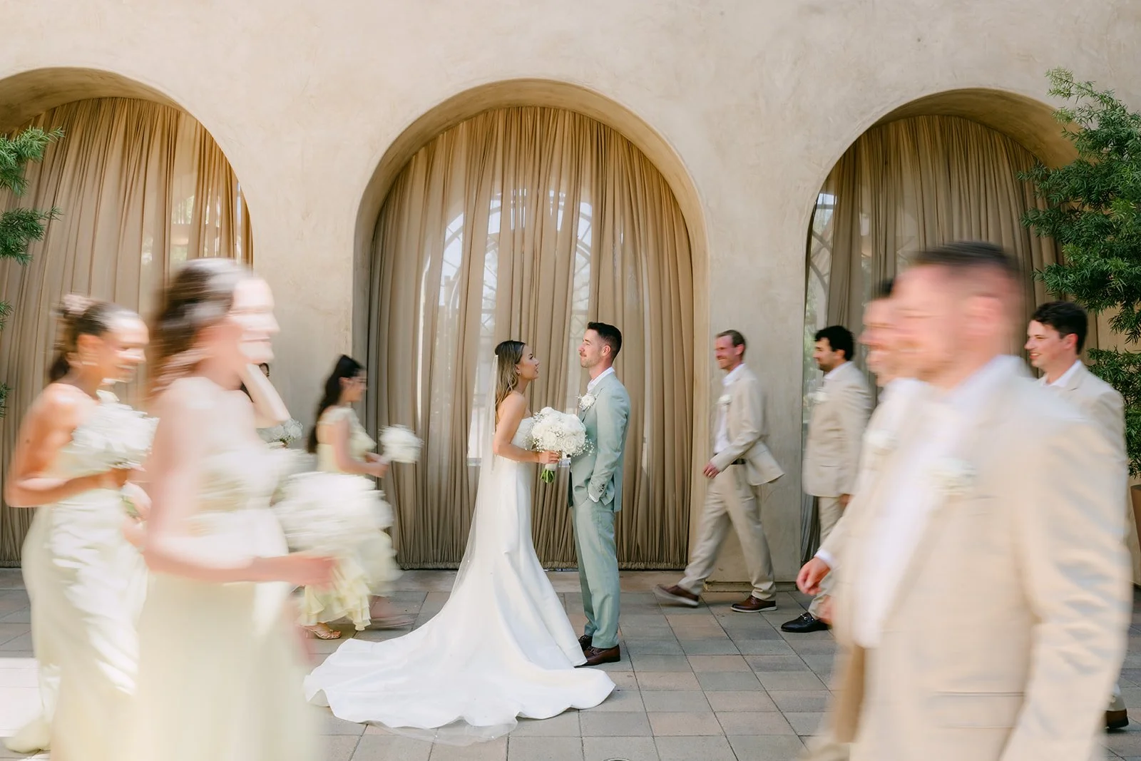 Groomsman walking past the bride and bridesmaids during wedding party photos