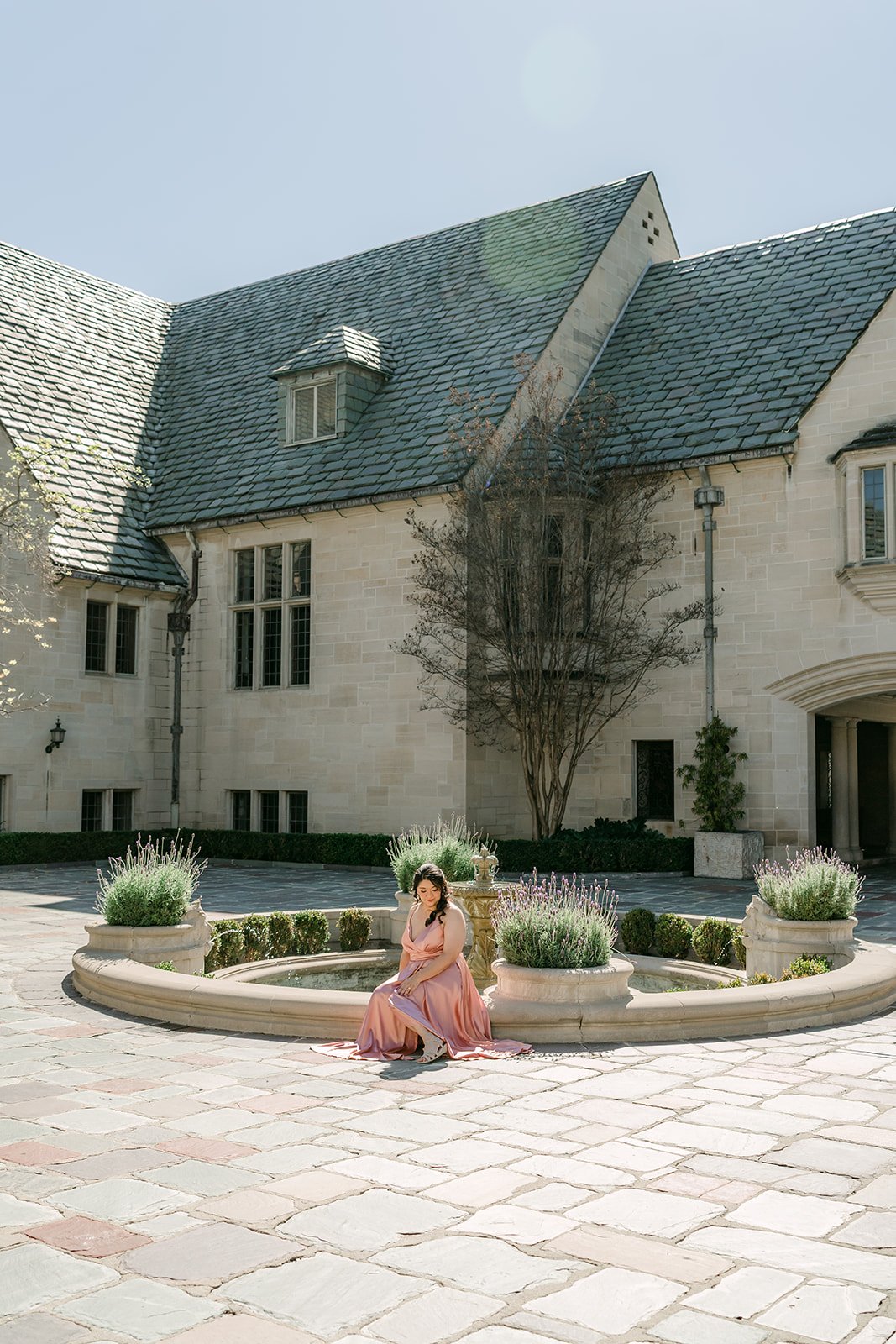 Wide view of the Tudor-style Greystone Mansion and its motor court with Saira at the fountain.