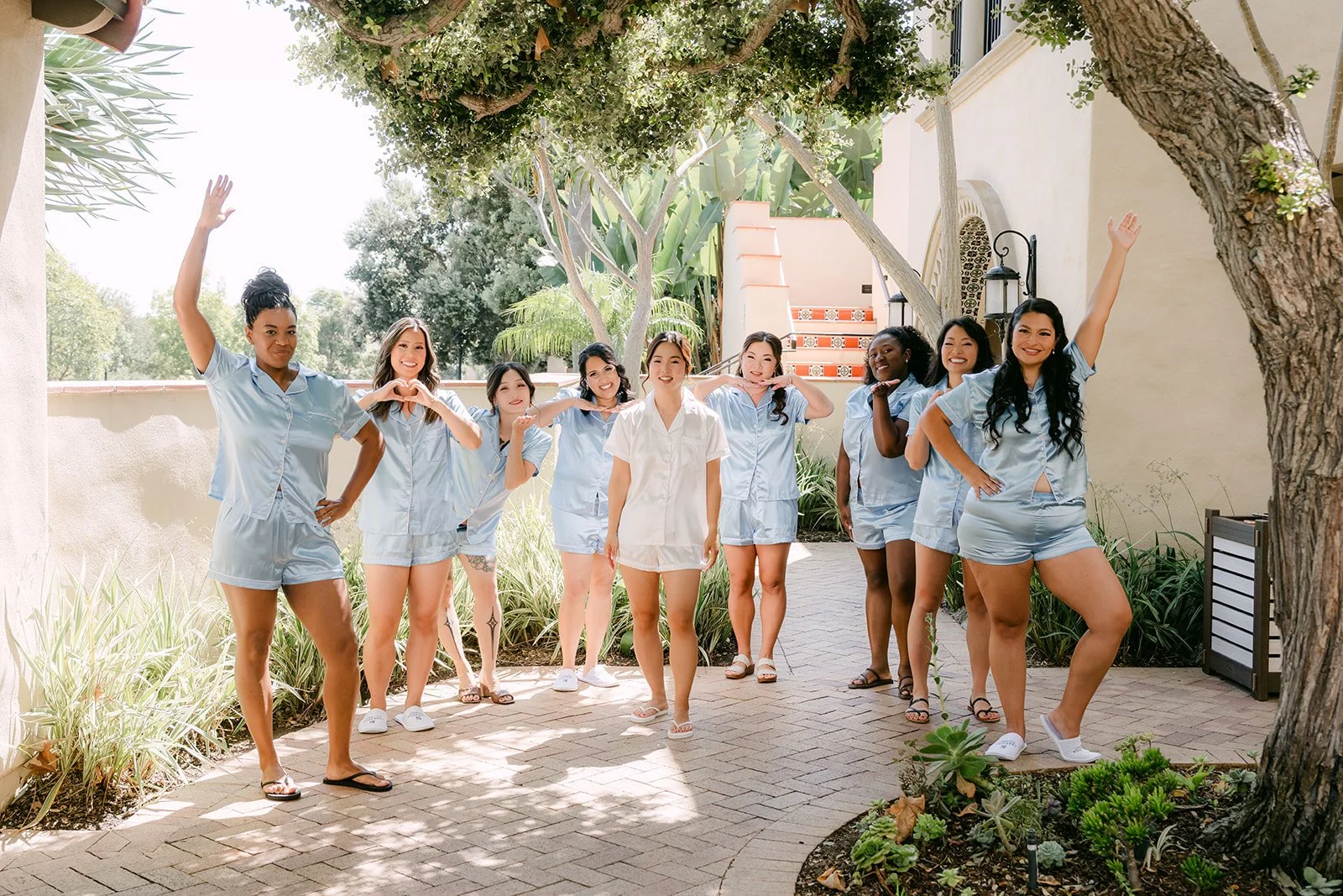 Bridesmaids in blue pajamas cheering on the lawn during getting ready