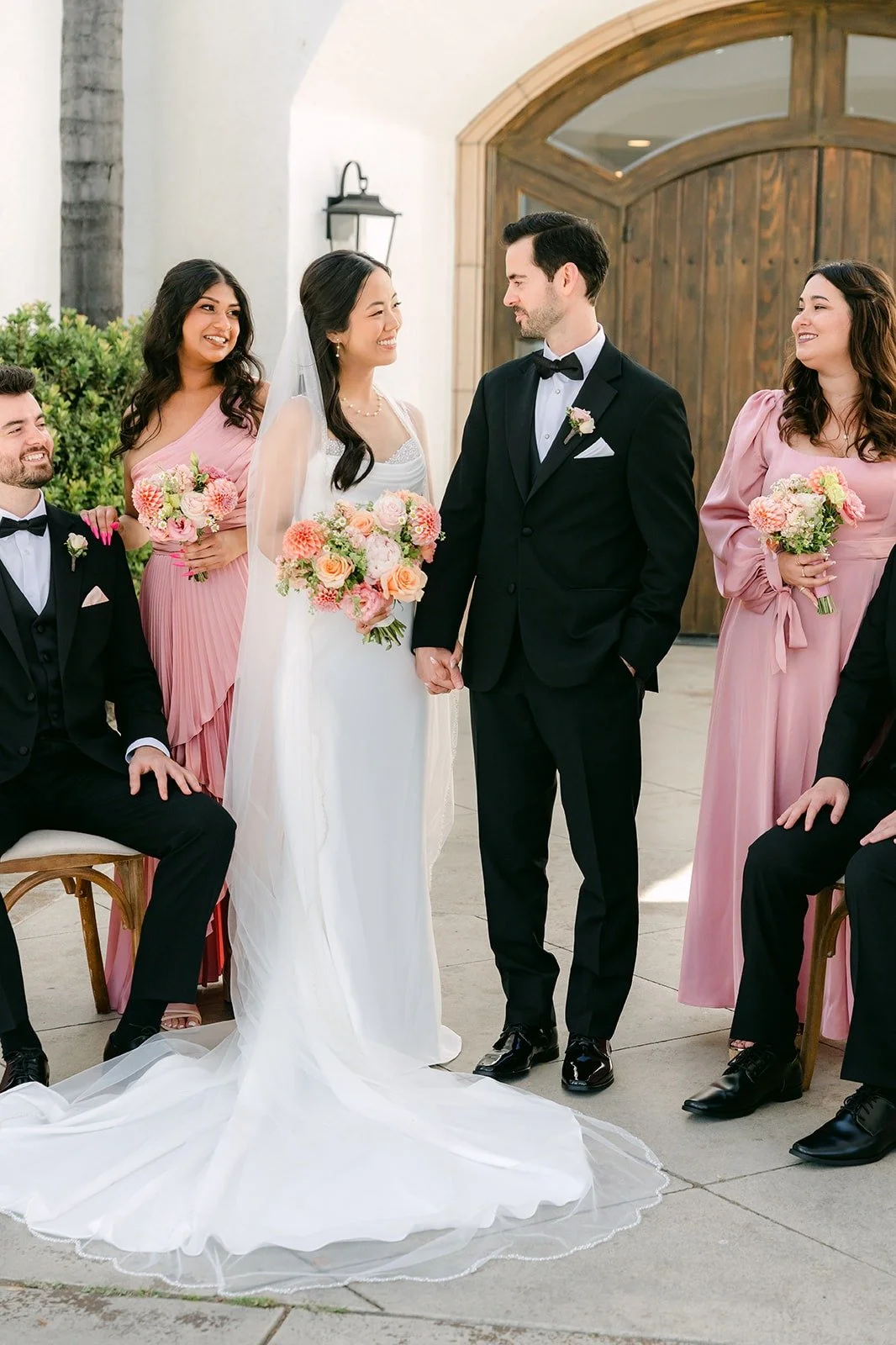 Stephanie and Kevin with their wedding party in front of the arched wooden doors