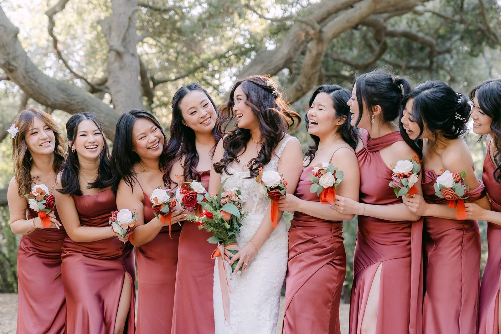 Shayna with her bridesmaids in rose colored gowns among the oaks