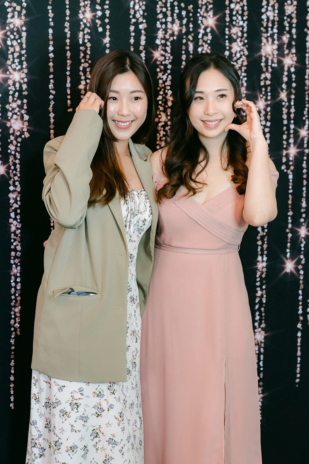Two guests pose in front of the photo booth backdrop