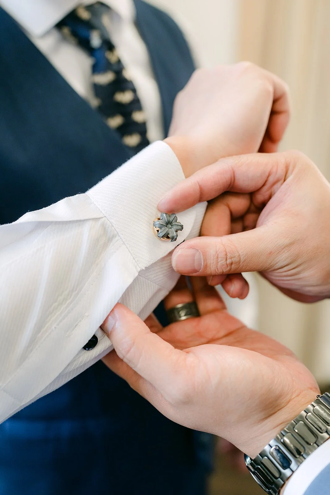 Close detail of Michael fastening his cufflinks.