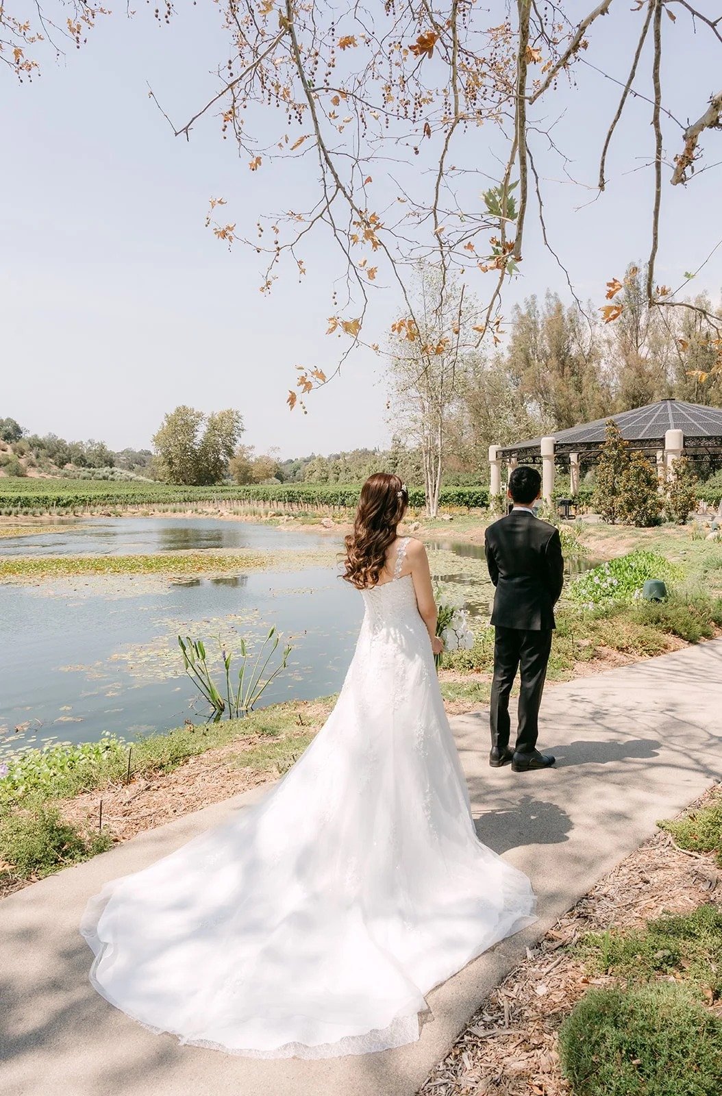 Marina approaching Tyler from behind on the path by the lake for their first look
