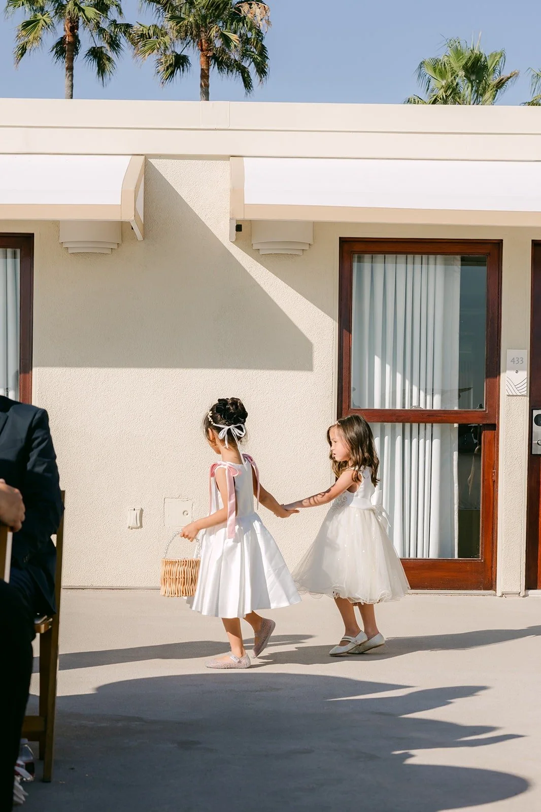 Two flower girls in white dresses tossing petals down the aisle