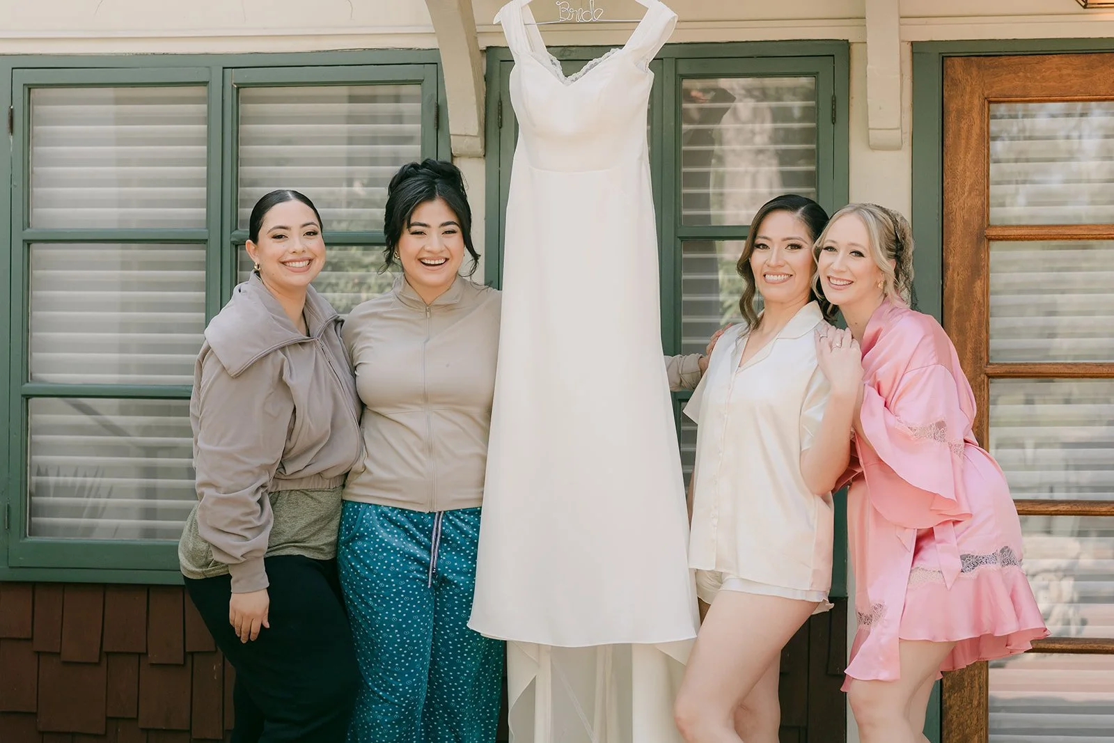 Mariana and her bridesmaids in robes beside the gown on the bridal suite porch