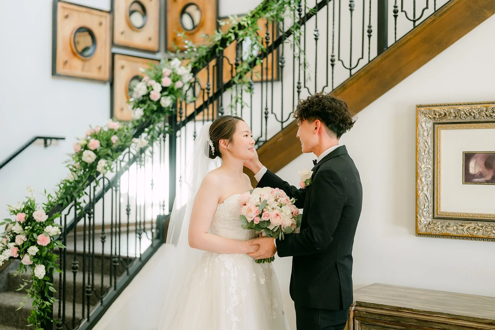 Groom touching the bride's face during the first look on the staircase