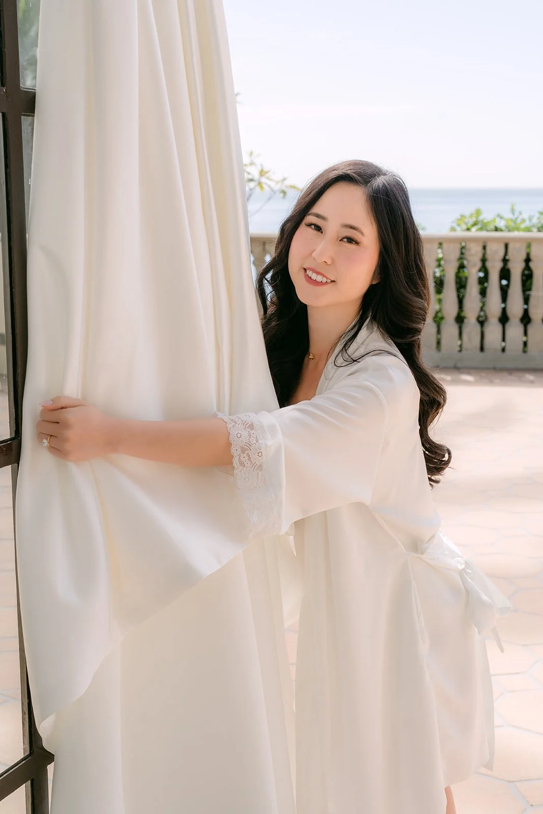 Bride smiling beside her wedding gown
