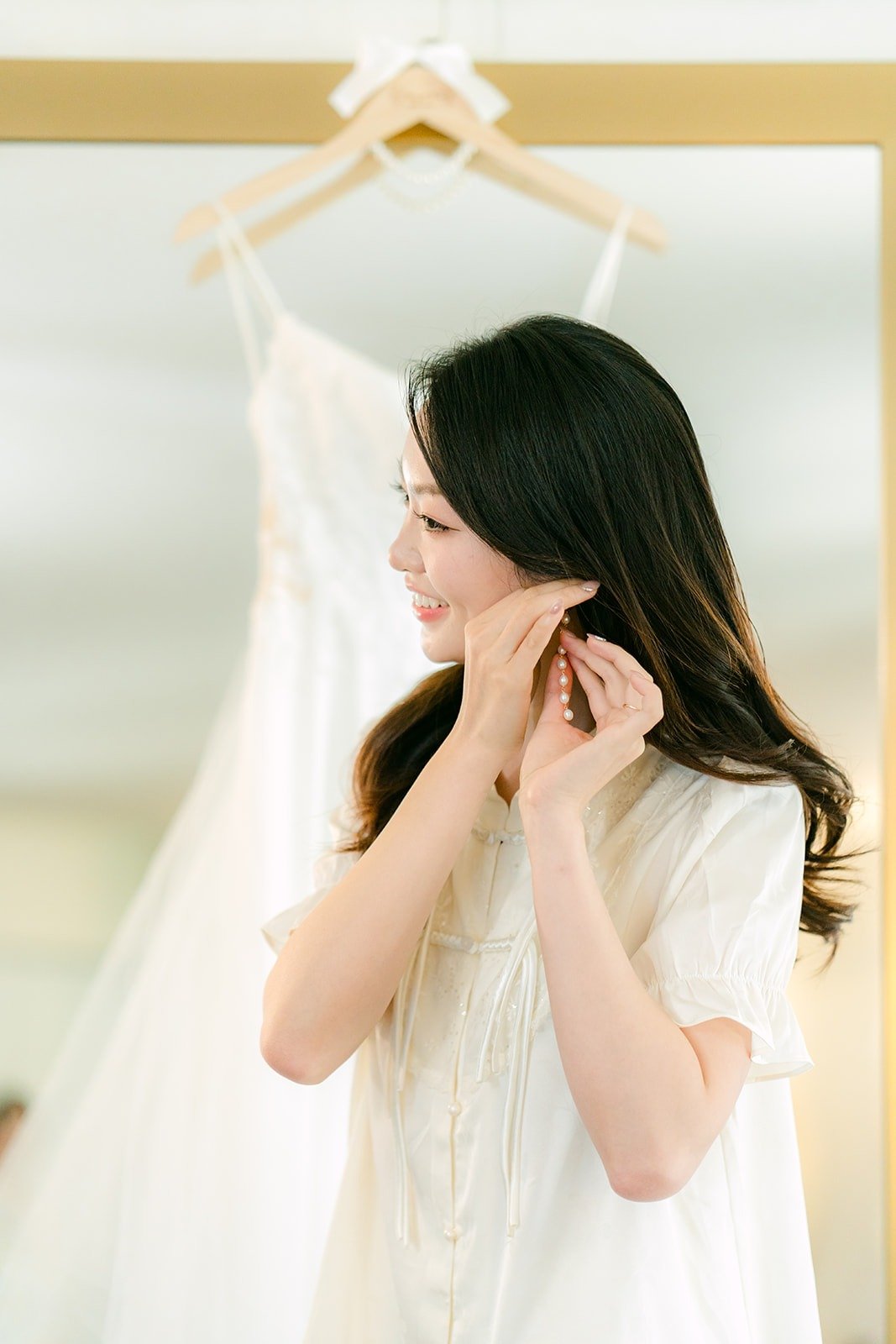 Tin putting on her earrings beside her dress